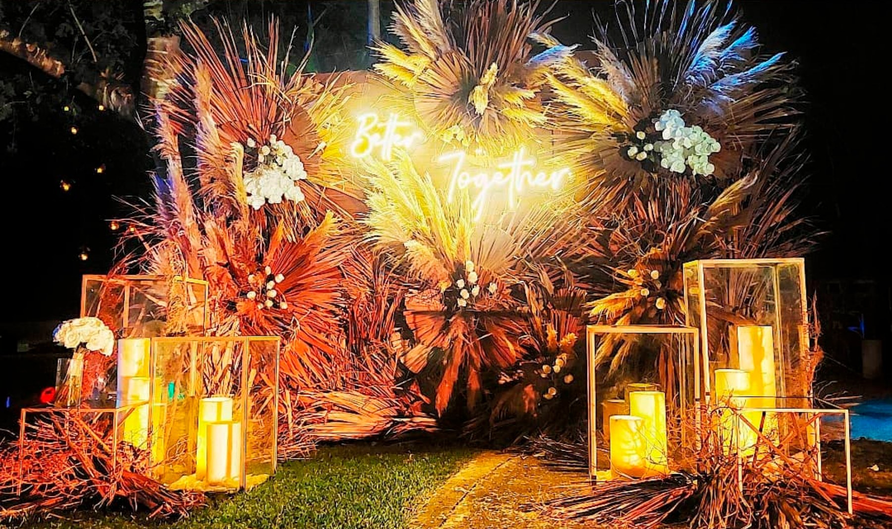 Diseño floral de evento con iluminación cálida y elementos tropicales